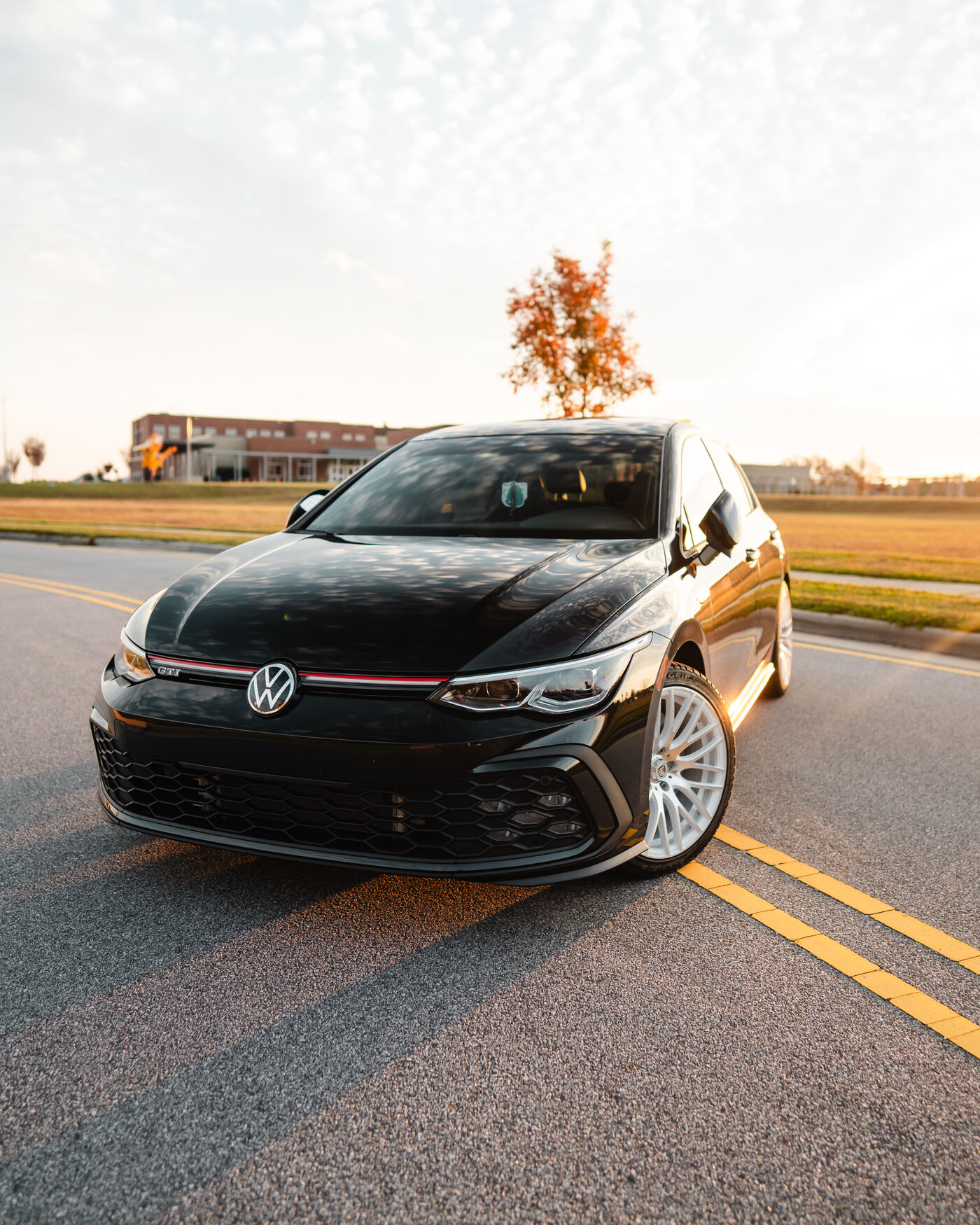 Black Volkswagen Golf GTI on road at golden hour
