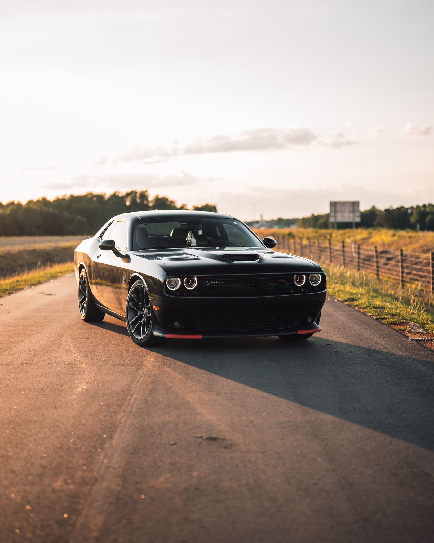 Black Dodge Challenger RT on country road at golden hour