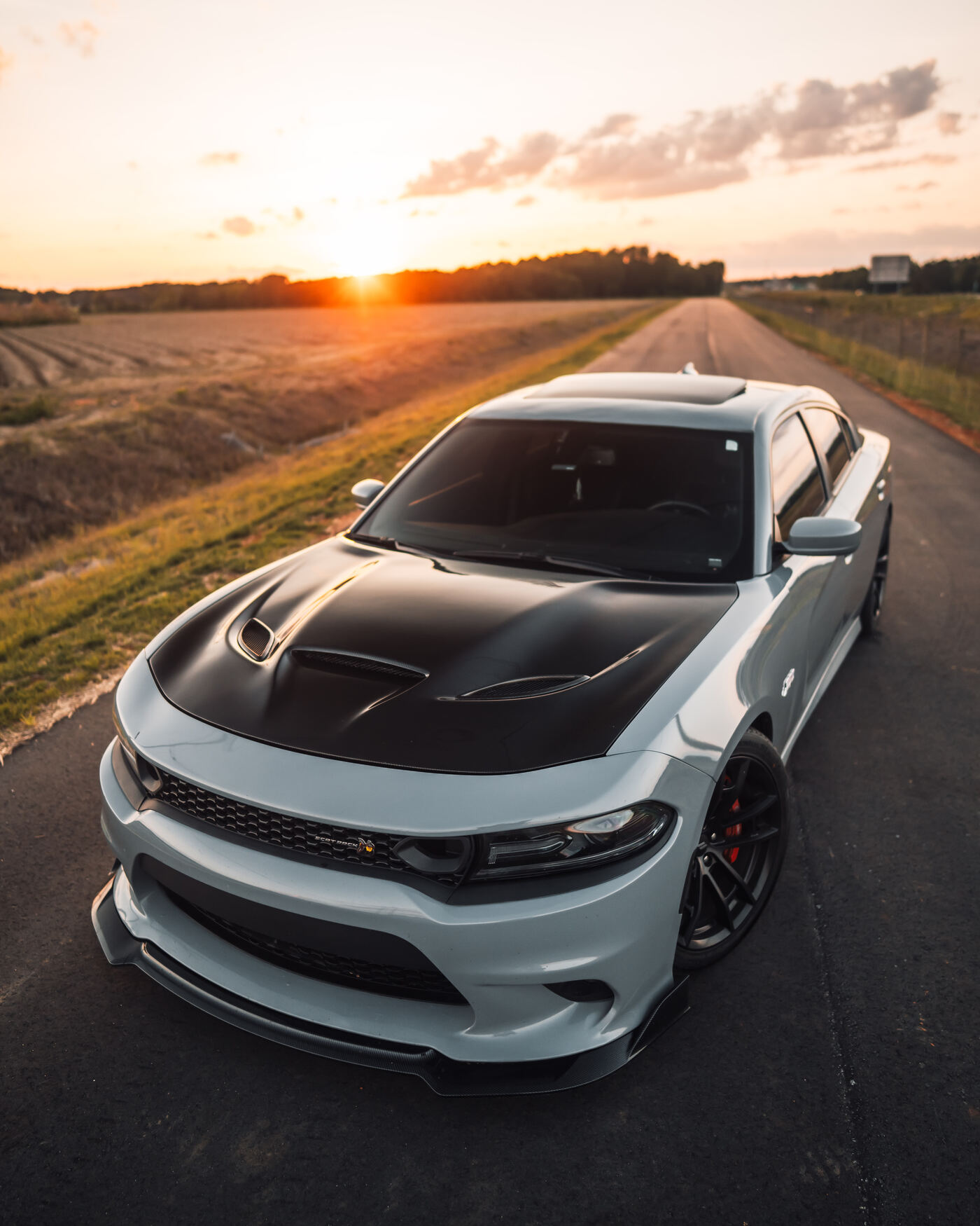 Grey Dodge Charger Hellcat on open road at sunset