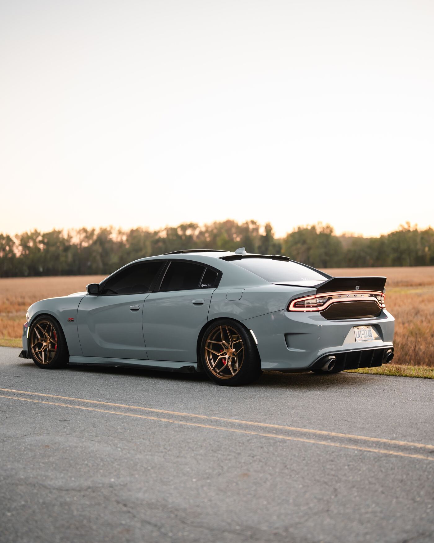 Grey Dodge Charger Scat Pack with gold wheels at sunset