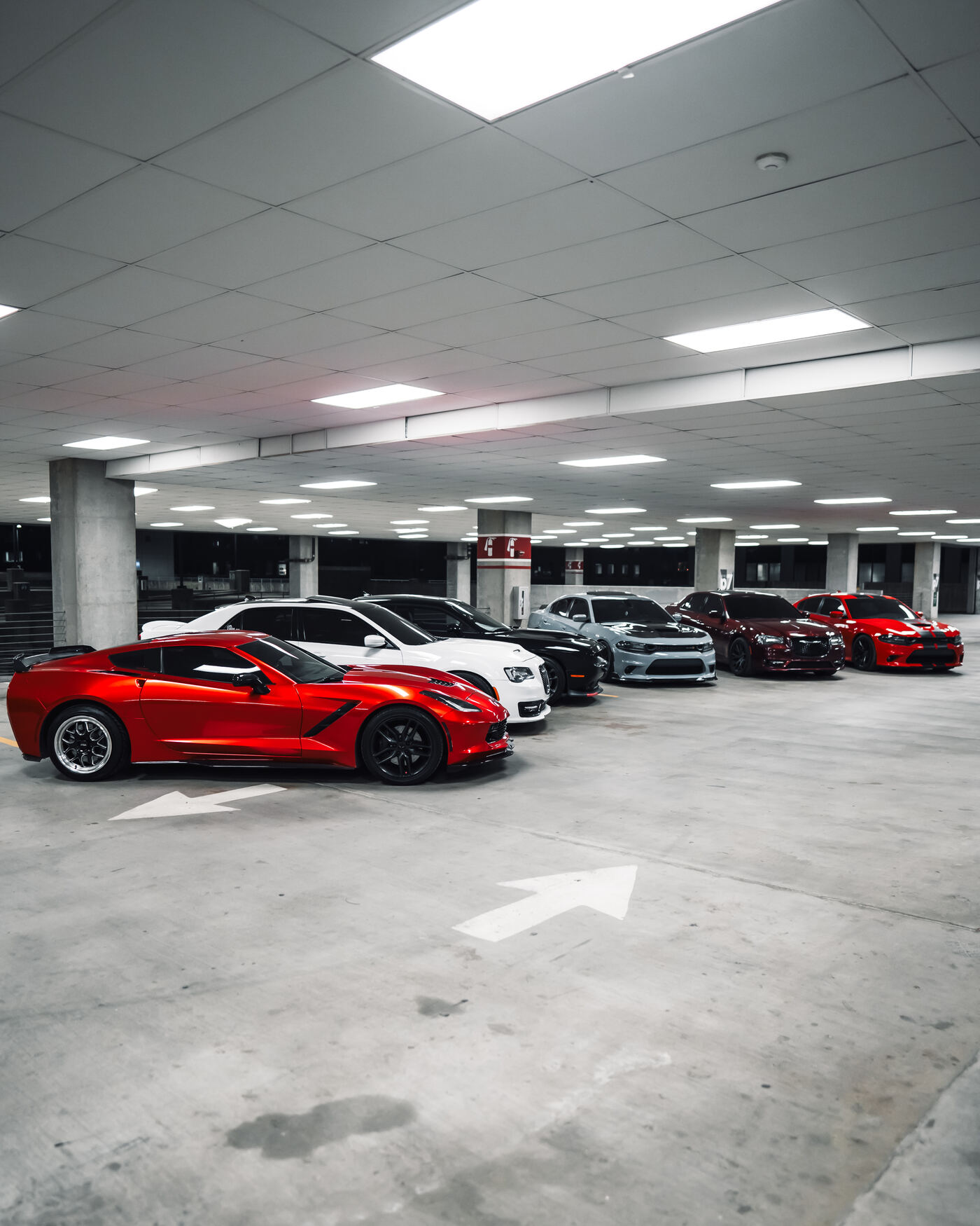 Traviesos crew lineup in parking deck — red Corvette leading white, black, grey and maroon cars